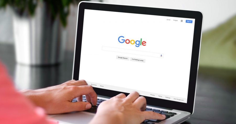 A woman typing on Google's search bar on a laptop.